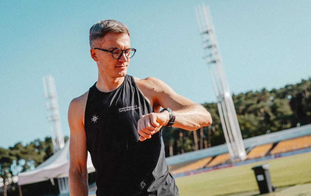 Piotr Tomczyk, trener biegania, sprawdza tempo treningu na zegarku sportowym.