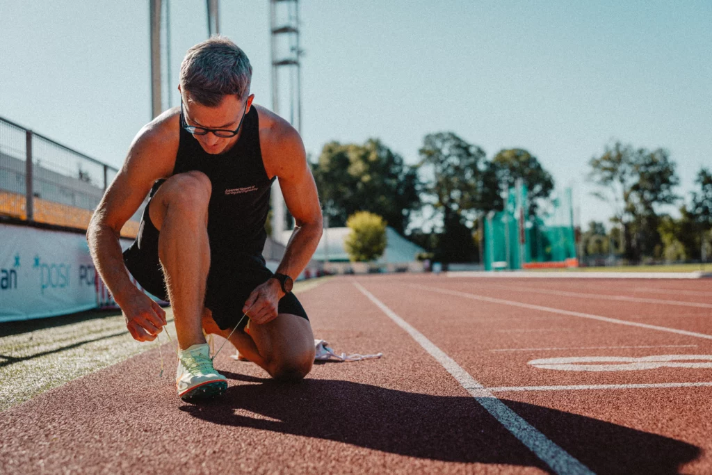Piotr Tomczyk, trener biegania, wiąże but na bieżni na stadionie lekkoatletycznym w Poznaniu.