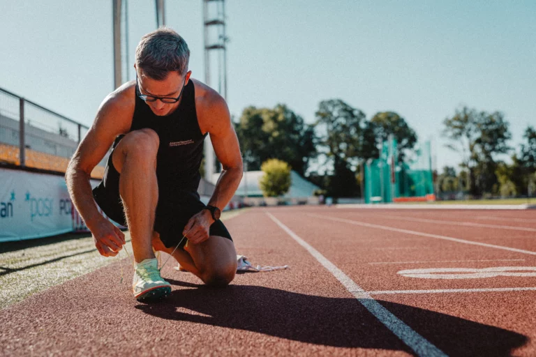 Piotr Tomczyk, trener biegania, wiąże but na bieżni na stadionie lekkoatletycznym w Poznaniu.