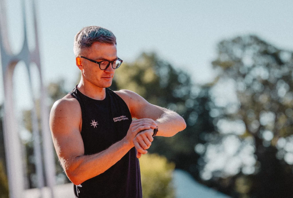 Piotr Tomczyk, trener biegania, sprawdza tempo treningu na zegarku sportowym.