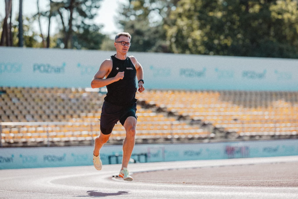 Piotr Tomczyk trener biegania biegnie na bieżni lekoatletycnej.
